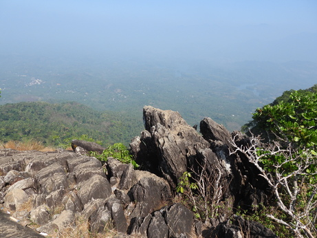 Scenic rockey mountain viewpoint with panoramic views of lush forests, rolling hills, and a mist covered valley in Kerala.